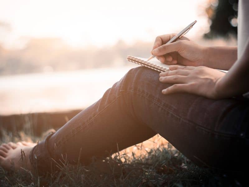 person sitting outside writing in journal
